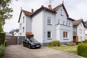 A two-story house with a car parked in the driveway.