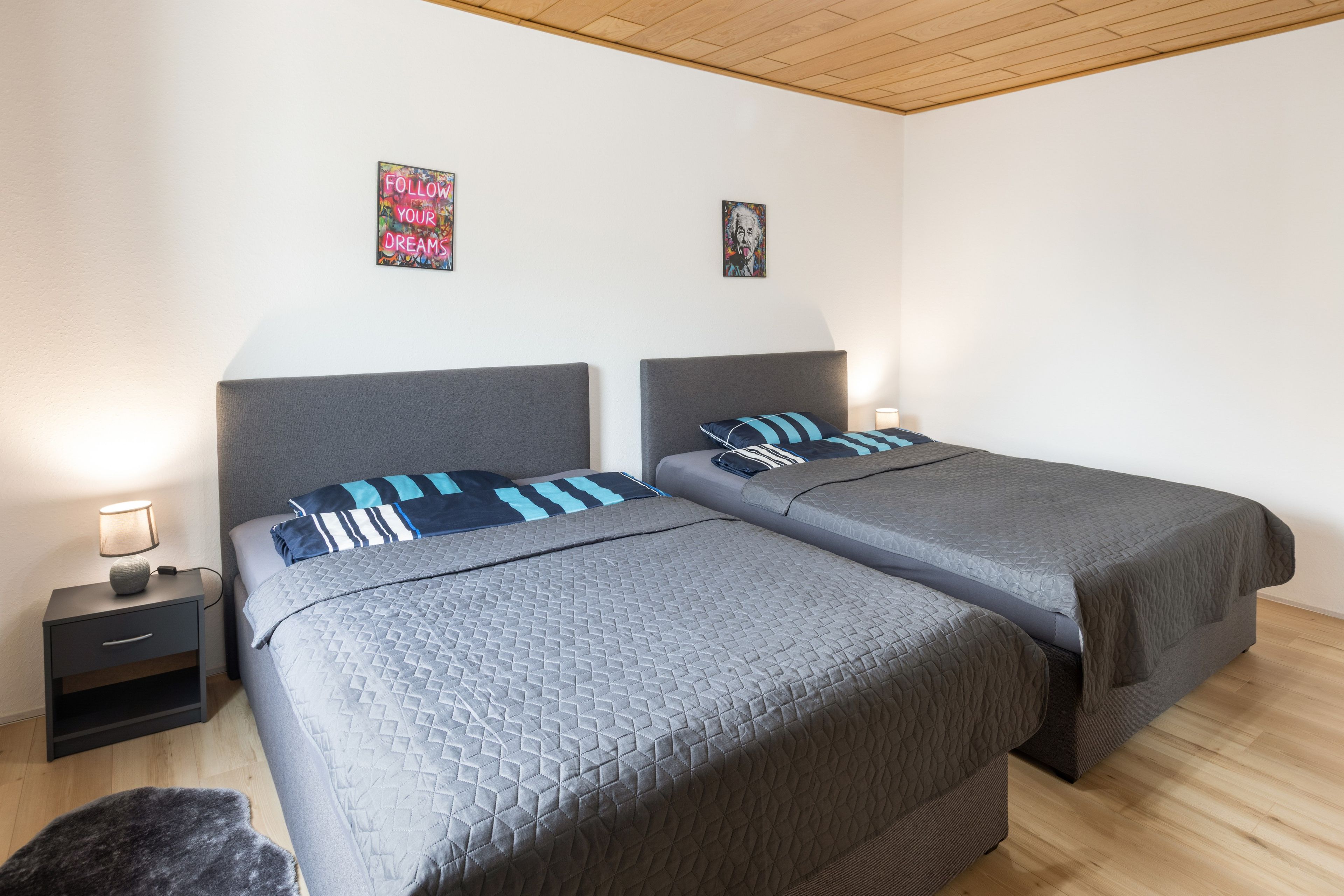 A double room with two beds, a nightstand, and a lamp.