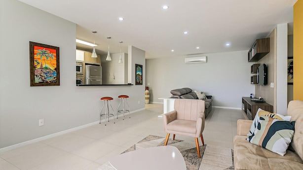 A modern living room with a sofa, a coffee table, and a kitchen area with a refrigerator and a microwave. - Ap in Resort 200m From the Beach Floripa-sc Mhe003 (Florianópolis)
