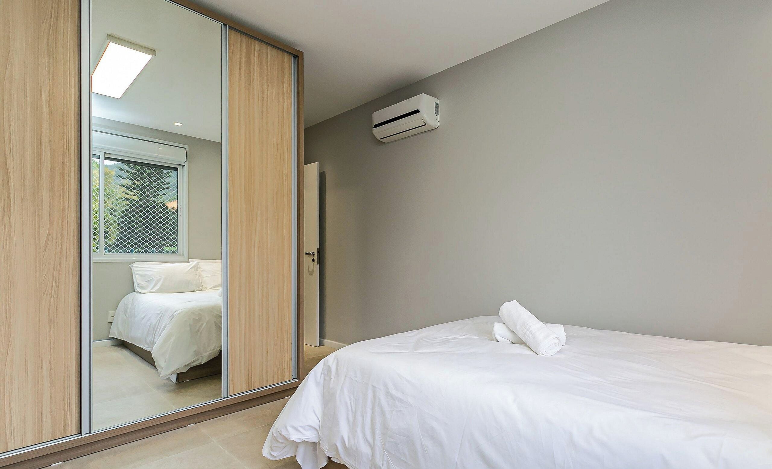 Un dormitorio con cama, espejo y equipo de aire acondicionado.