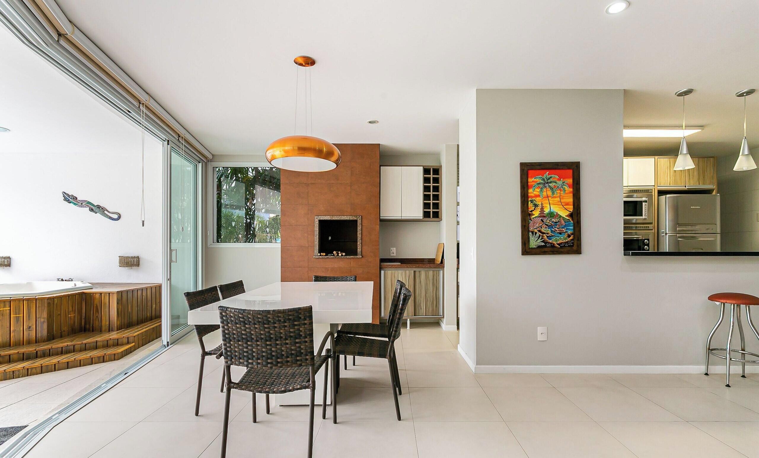 Una cocina moderna con electrodomésticos integrados, un comedor con mesa de vidrio y sillas de mimbre, y un ventanal que proporciona luz natural.