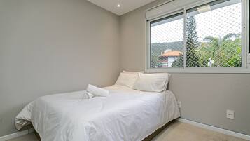 A bedroom with a bed, a window with a view, and a light switch on the wall.