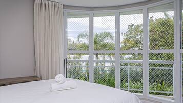 Une chambre avec une grande fenêtre, un lit et un rideau.