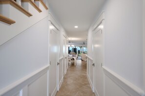 A hallway with white walls and wooden trim, leading to a dining area with a view of the ocean. - Dunes of Boca 2 | 3 bedroom 3 Bath | Pool | Gulf Front | Tennis | Sleeps 6 (Boca Grande)