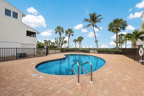A swimming pool with a brick deck, surrounded by palm trees and a fence. - Dunes of Boca 2 | 3 bedroom 3 Bath | Pool | Gulf Front | Tennis | Sleeps 6 (Boca Grande)