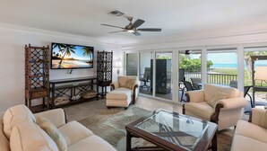 Una sala de estar con televisión, asientos y vistas al océano.