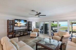 A living room with a television, seating, and a view of the ocean. - Dunes of Boca 2 | 3 bedroom 3 Bath | Pool | Gulf Front | Tennis | Sleeps 6 (Boca Grande)