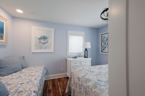 A bedroom with two beds, a dresser, a window with blinds, and artwork on the walls. - Dunes of Boca 2 | 3 bedroom 3 Bath | Pool | Gulf Front | Tennis | Sleeps 6 (Boca Grande)