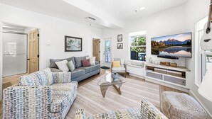 Una sala de estar moderna con un sofá, sillones, una mesa de centro y un televisor.