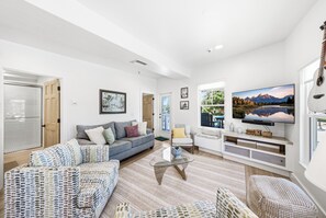 Ein modernes Wohnzimmer mit Sofa, Sesseln, Couchtisch und Fernseher.
