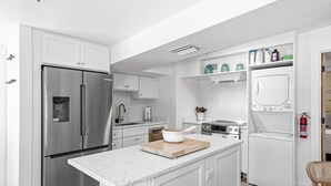Una cocina moderna con electrodomésticos de acero inoxidable, armarios blancos y encimera de granito.