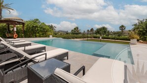 A swimming pool with lounge chairs and a pergola. - La Manga Club Individual Villa 619 (Atamaría)