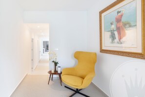 A modern interior with a yellow armchair, a framed painting, and a small table with a vase of flowers. - La Manga Club Individual Villa 619 (Atamaría)
