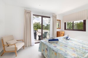 Ein Hotelzimmer mit einem Bett, einem Sessel, einem kleinen Tisch und einem Fenster.
