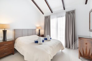 A hotel room with a bed, bedside tables, a lamp, a wardrobe, and a window with curtains. - La Manga Club Individual Villa 619 (Atamaría)
