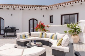 Un patio con mobili da esterno, un barbecue e piante in vaso.