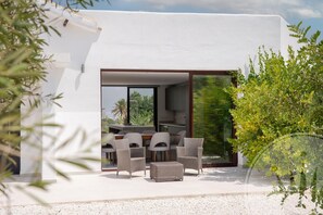 A modern outdoor dining area with wicker furniture and a view of the greenery. - La Manga Club Individual Villa 619 (Atamaría)