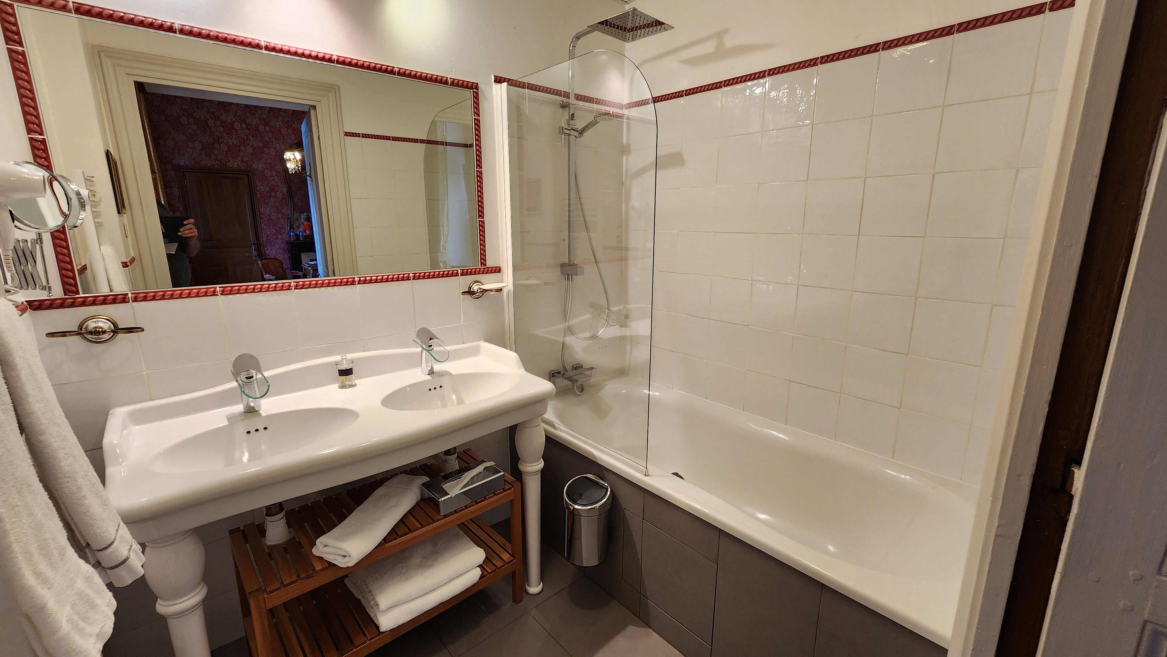 A bathroom with a white sink, two mirrors, a glass-enclosed shower, and a bathtub.