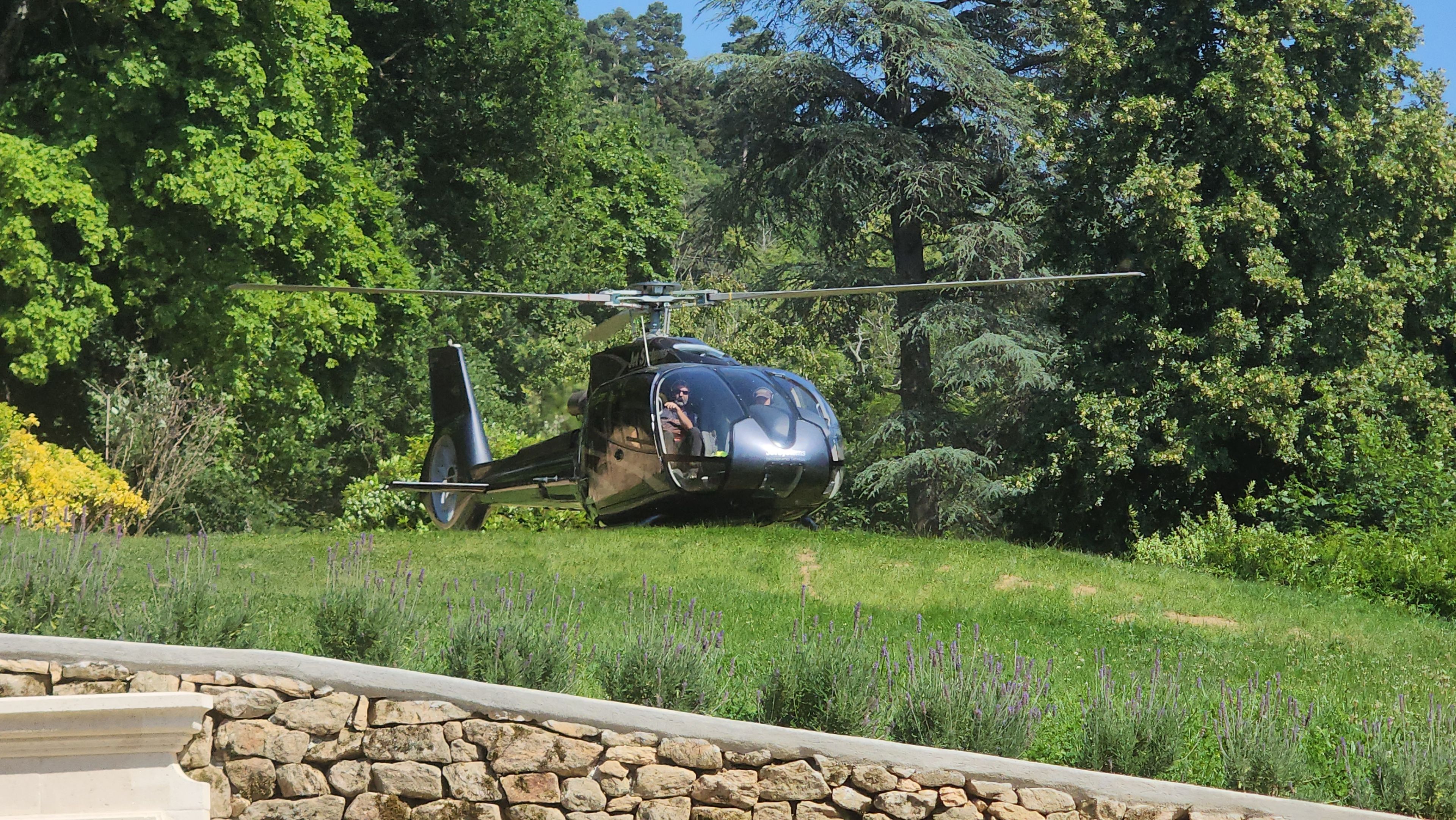 A helicopter parked on a grassy area with trees in the background.