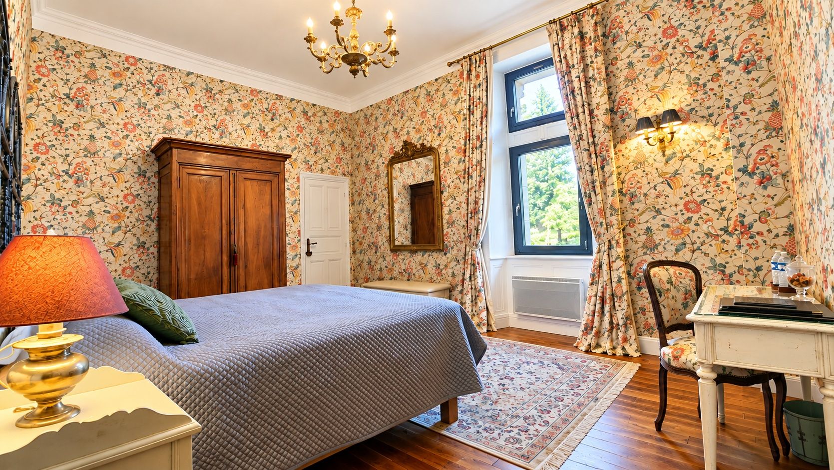 Un dormitorio con cama, mesita de noche, cómoda, espejo, ventana con cortinas y candelabro.