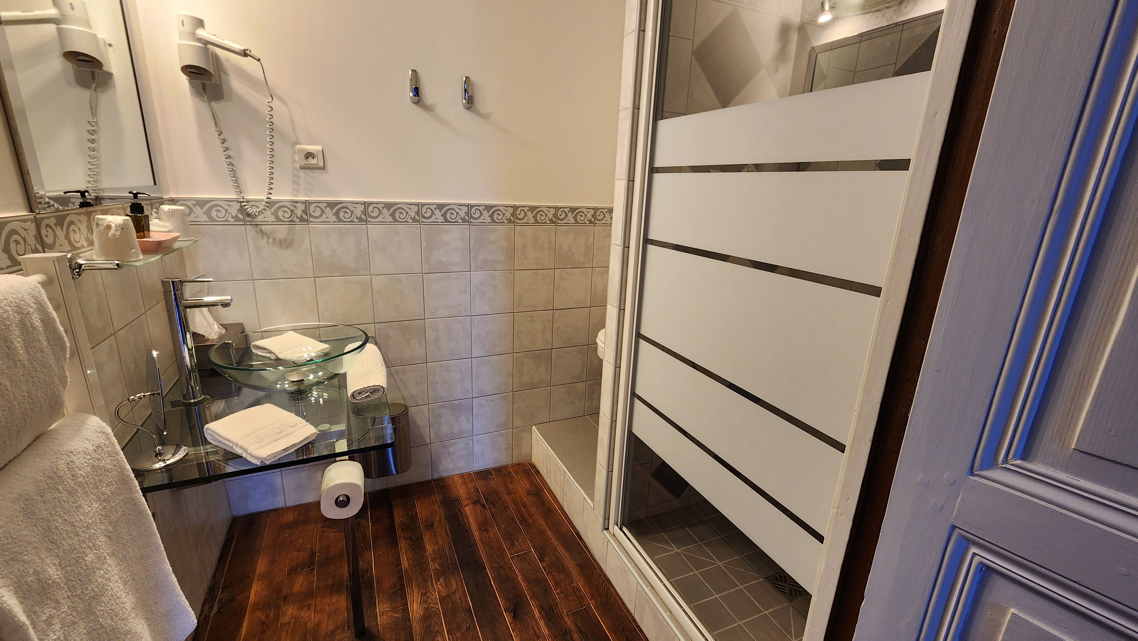 Un baño con cabina de ducha de vidrio, un perchero, un inodoro y un espejo.
