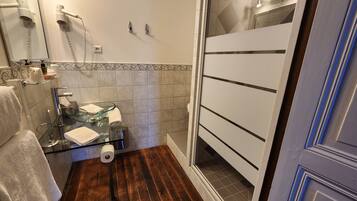 Un baño con cabina de ducha de vidrio, un perchero, un inodoro y un espejo.