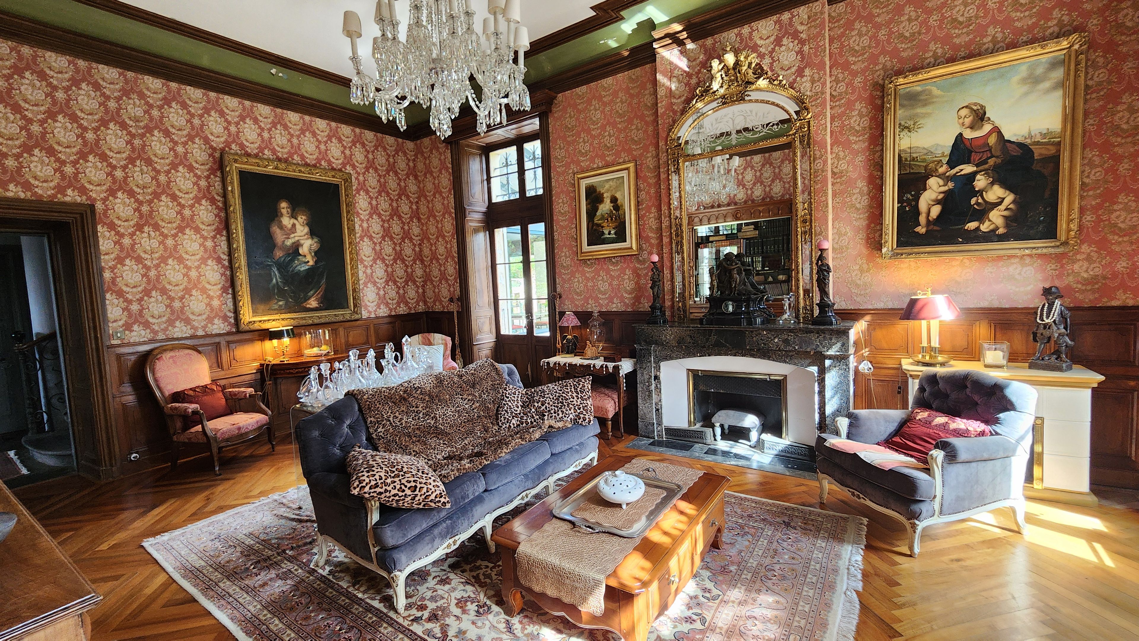Une pièce avec une cheminée, un canapé, un fauteuil et une table avec une lampe.