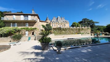 Un grande edificio in pietra con piscina, area relax all'aperto e rigogliosa vegetazione.