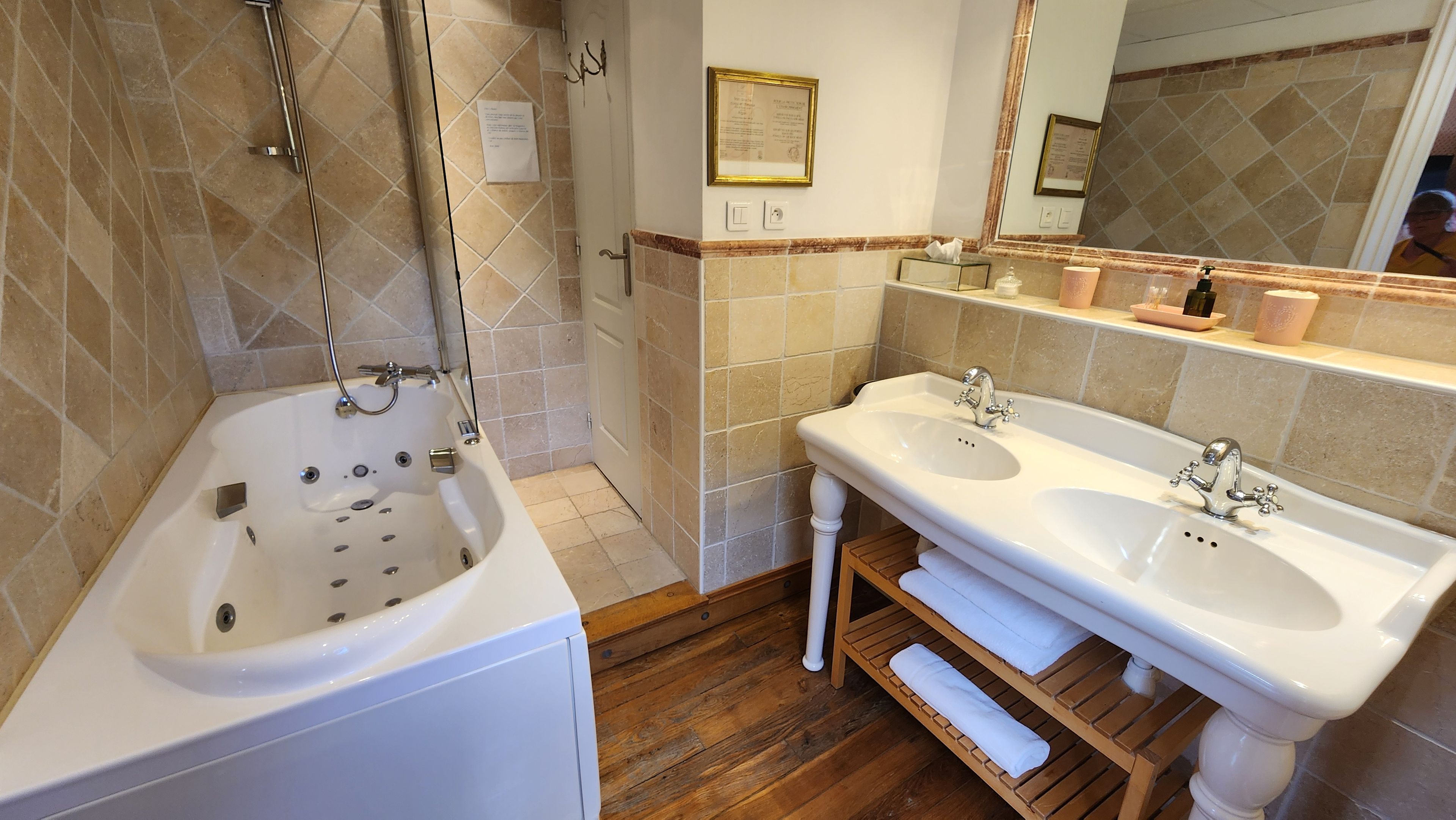 Een badkamer met een bad, twee wastafels, een spiegel en een houten plank.