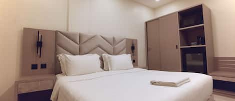 Un dormitorio moderno con una cama grande, un armario empotrado y una mesita de noche.