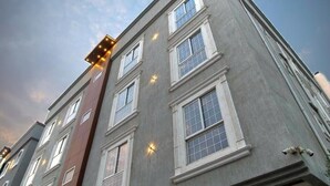 A multi-story building with a modern architectural style, featuring a series of windows and a visible entrance with a door. - Jada  Apartments (AL KHOBAR)