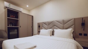 A hotel room with a bed, a wardrobe, a desk, and a wall-mounted phone. - Jada  Apartments (AL KHOBAR)