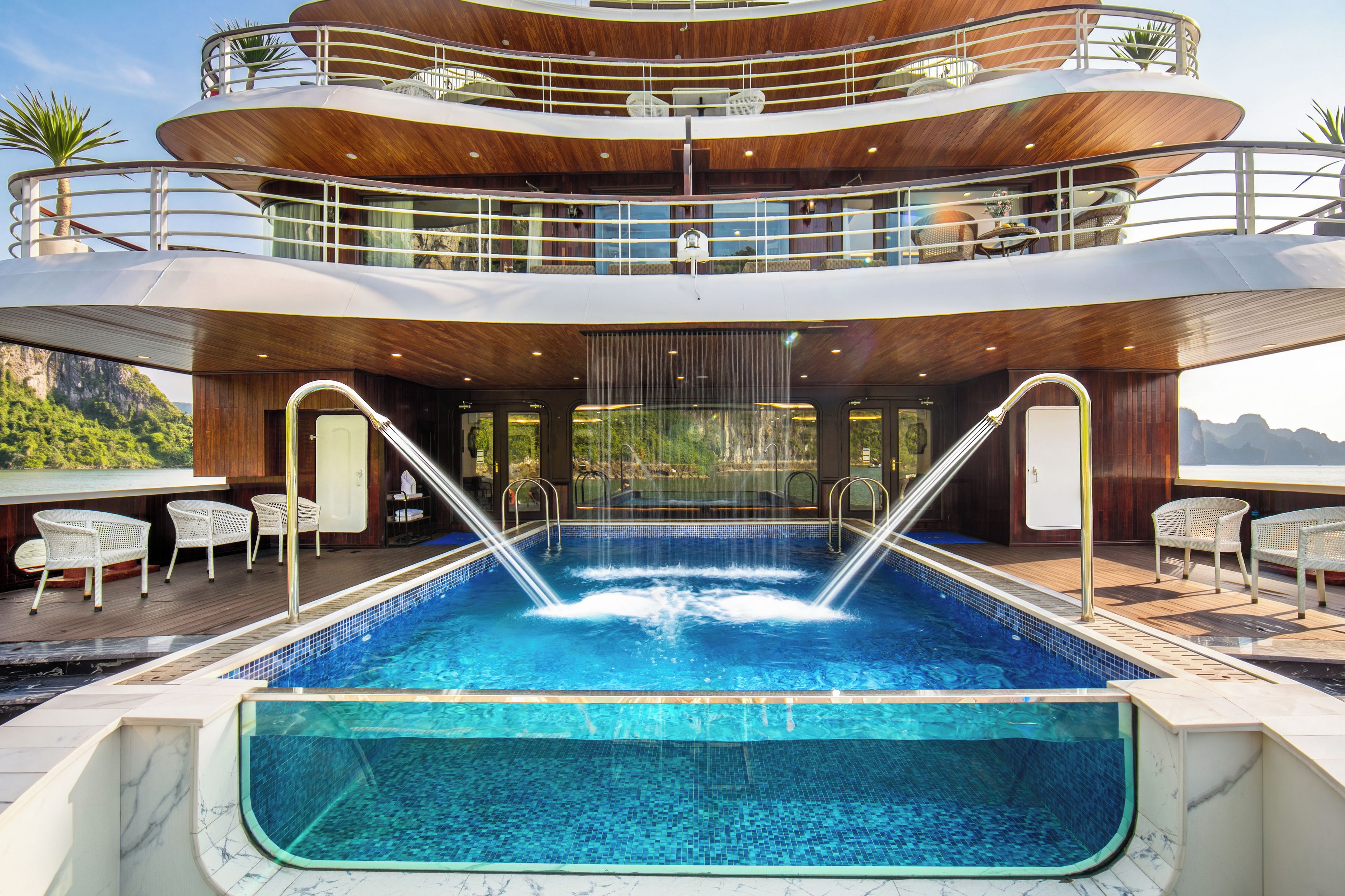 Un espace piscine à plusieurs niveaux, comprenant un jacuzzi, des chaises longues et une vue sur le paysage environnant.