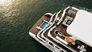 Convés de navio de cruzeiro com piscina, espreguiçadeiras e área de refeições.