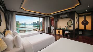 Une chambre d’hôtel avec deux lits, un balcon donnant sur la mer, une salle de bain et un petit coin salon.