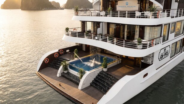 Um navio de cruzeiro com várias plataformas, piscina no convés inferior, área de estar externa e um salva-vidas na lateral.