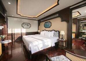 Una habitación de hotel con una cama grande, una mesita de noche, una lámpara y un espejo.