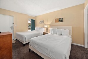 Camera d'albergo con due letti, una scrivania e una finestra con tende.