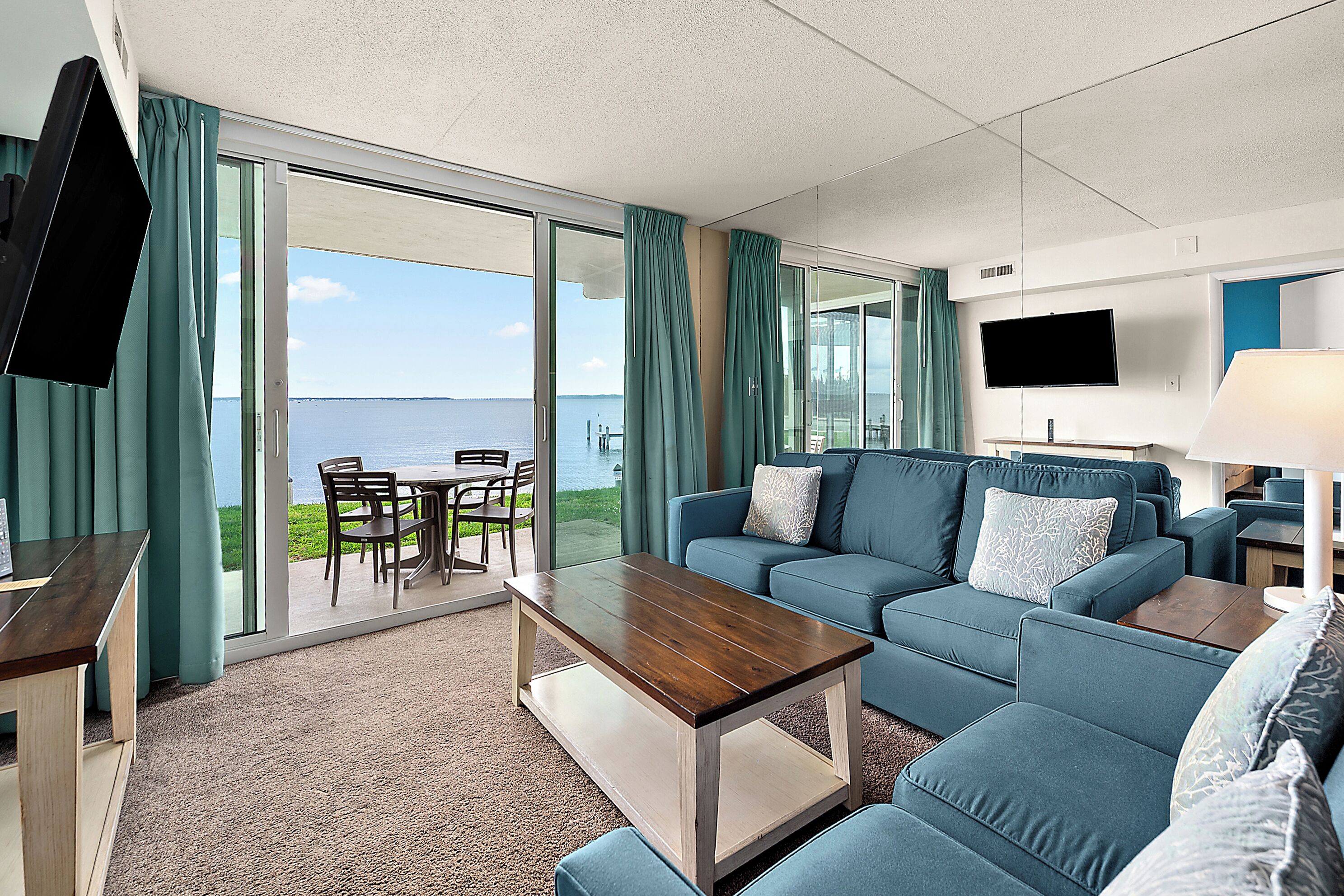 Une chambre d’hôtel avec un canapé, une table basse, un téléviseur et une vue sur la mer.