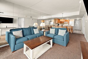 Un soggiorno moderno con un divano blu, un tavolino in legno e un'area pranzo con sedie e tavolo di legno.