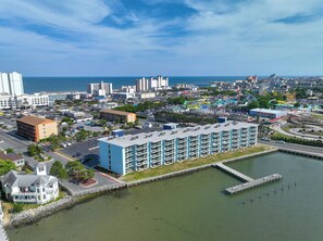 A coastal cityscape with a marina, a large hotel with multiple floors and balconies, and a theme park in the background. - Bayfront Retreat Near Jolly Roger | Indoor Pool & Private Patio (Ocean City)