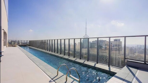 A rooftop swimming pool with a glass railing, offering a city view. - Studio in Cond. w/ Pool in Paraiso Onp1701 (São Paulo)