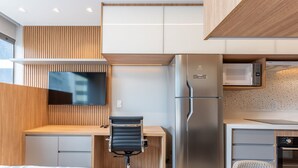 Eine moderne Küche mit Einbau-Mikrowelle, Kühlschrank und einem flachbildschirmigen Fernseher an der Wand.