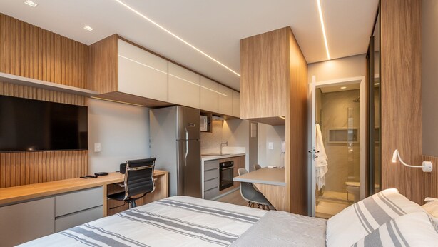 Ein modernes Schlafzimmer mit einem großen Bett, einem Schreibtisch und einer Küchenzeile.