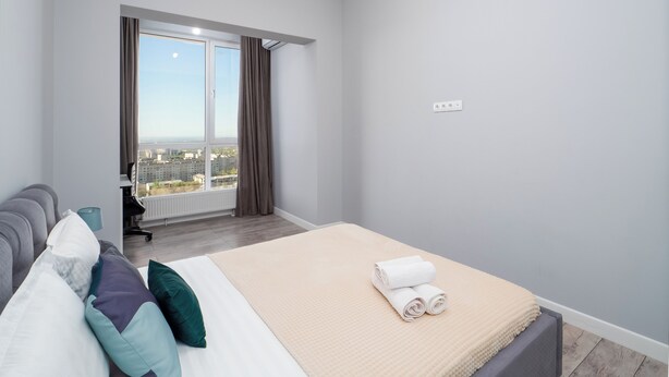 Et moderne hotelværelse med en stor seng, en sofa, udsigt til byen og et vindue med gardiner.