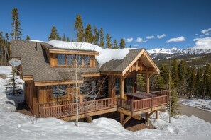 A wooden cabin with a deck, surrounded by snow and trees, with a mountain backdrop. - New to VRBO! Ski-in/out in 15 Steps - Alpine Meadows Chalet - Hot Tub -Mtn Views (Big Sky)