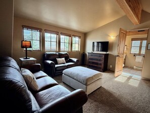 A living room with a leather sofa, a television, and a fireplace. - New to VRBO! Ski-in/out in 15 Steps - Alpine Meadows Chalet - Hot Tub -Mtn Views (Big Sky)