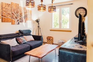 A modern living room with a sofa, a wooden coffee table, a floor lamp, and artwork on the wall. - Le Grand Duc: Lake view and close to downtown (Gérardmer)