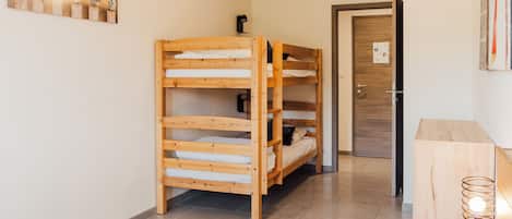 Une chambre avec un lit superposé, une tête de lit en bois, une table de chevet avec une lampe et un tableau accroché au mur.