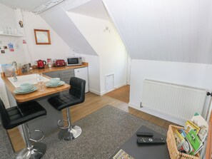 Eine kompakte Küche mit Essbereich, inklusive Tisch mit Stühlen, einer Mikrowelle, einem Wasserkocher und einem Kühlschrank.